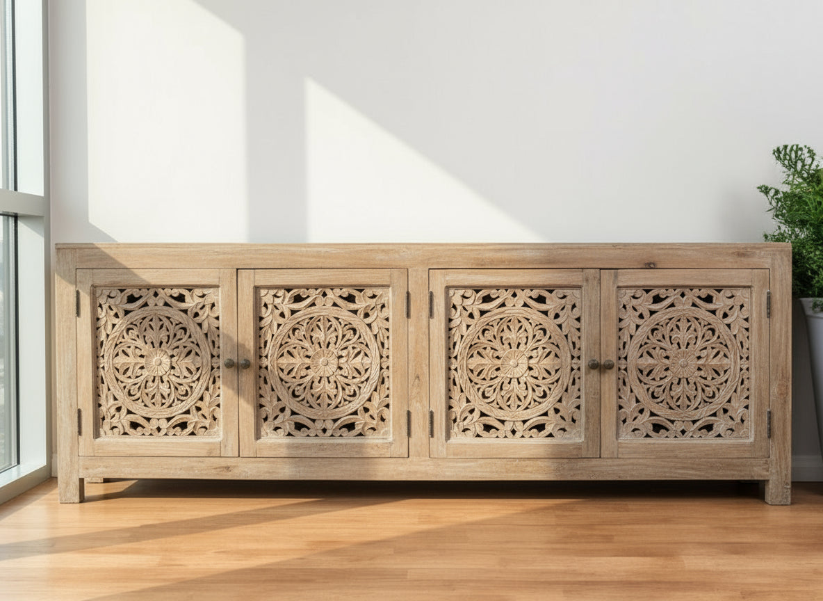 Wooden sideboard with intricate carvings on a wooden floor against a white wall.