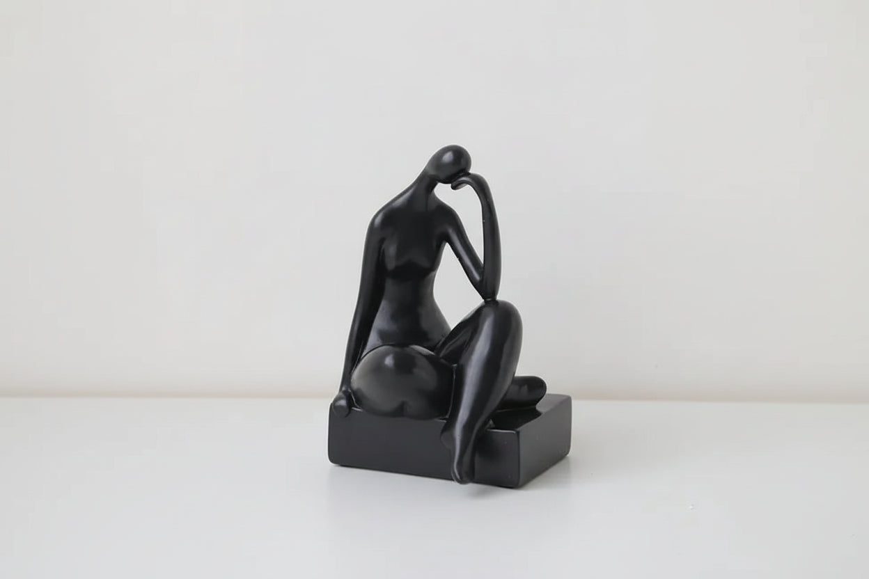 A black minimalist bookend decor in the shape of a figure sitting with their hands behind their head. Dimensions are shown: 21 cm in height, 10 cm in width, and 10 cm in depth.