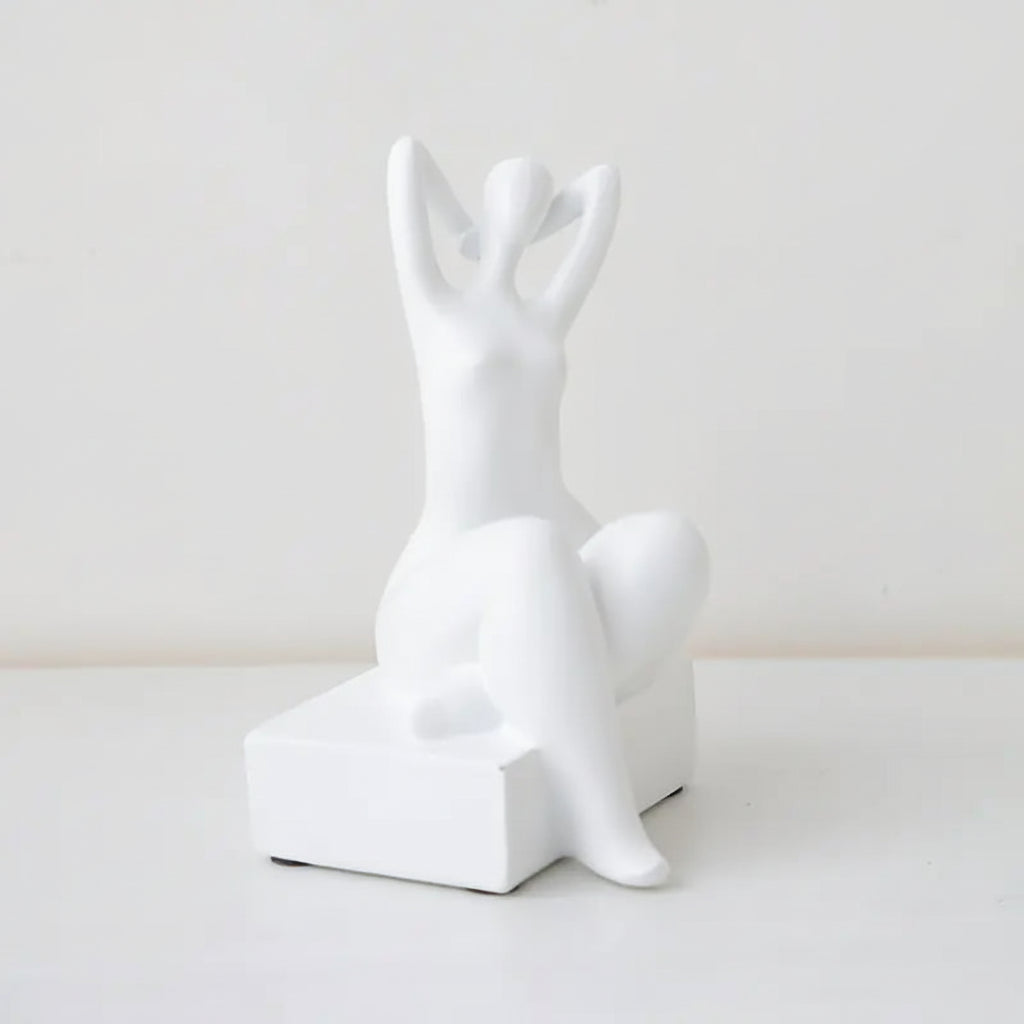 A black minimalist bookend decor in the shape of a figure sitting with their hands behind their head. Dimensions are shown: 21 cm in height, 10 cm in width, and 10 cm in depth.