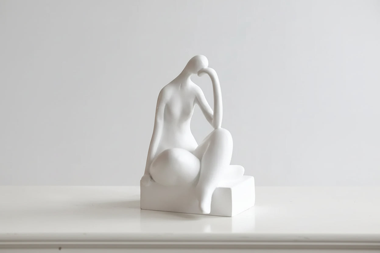 A black minimalist bookend decor in the shape of a figure sitting with their hands behind their head. Dimensions are shown: 21 cm in height, 10 cm in width, and 10 cm in depth.